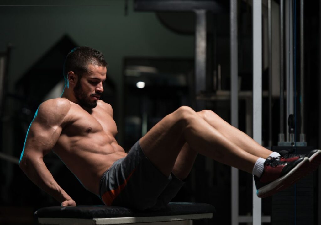 Ab exercises on a bench: man doing seated knee tucks on a weight bench