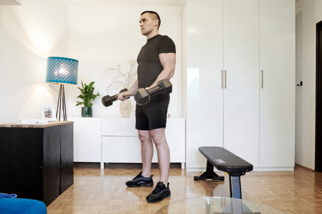 Man doing biceps curls with dumbbell to barbell converter